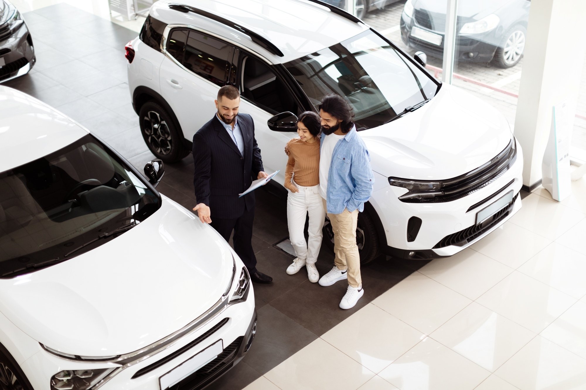 Asesor comercial de autos mostarando vehiculo de importación de procedencia asiatica a pareja joven interesados en comprarlo